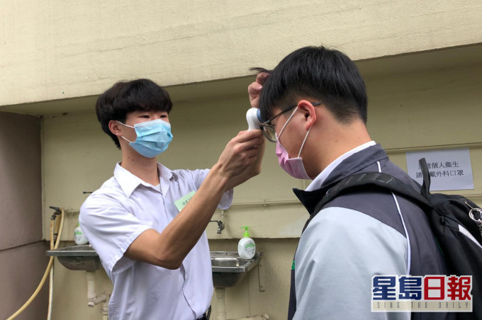 林同學(左)擔任健康活動工作人員,在校門當值,為同學量度體溫。