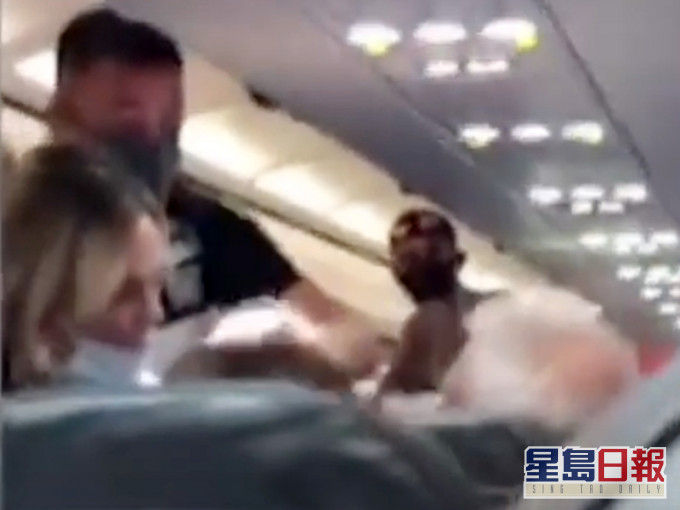 男子被摑後惱羞成怒,欲報復妻子,幸附近乘客見狀立即站起身阻止。影片截圖