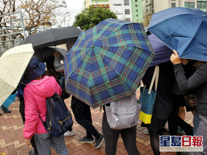 被告在傘陣掩護下離開法院。 資料圖片