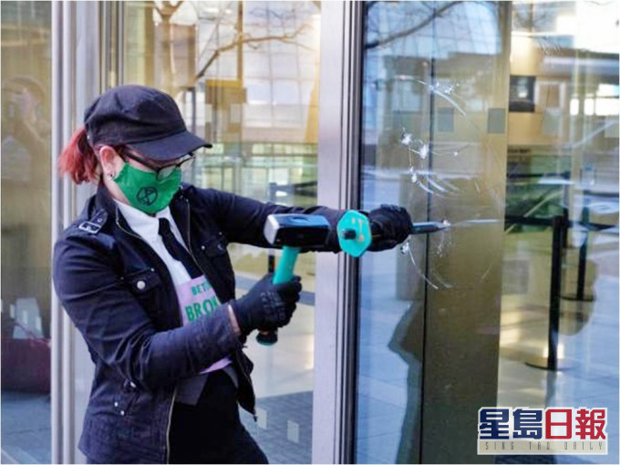 环保团体「反抗灭绝」的示威者用锤仔打破银行的玻璃窗。网图