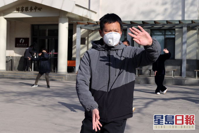 北京市民佩戴口罩在玉渊潭公园晨练。