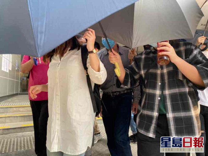 被告庄子东在伞阵下离开法院。(中间格仔恤衫蓝口罩)张旭珊摄