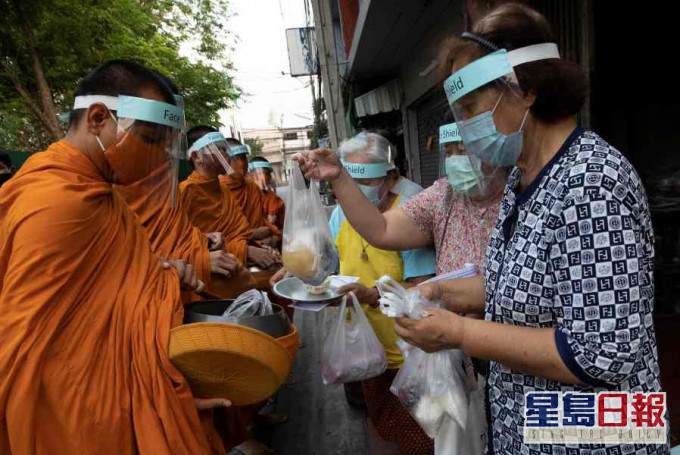曼谷有僧侣因应疫情,外出时戴上防护装备。AP