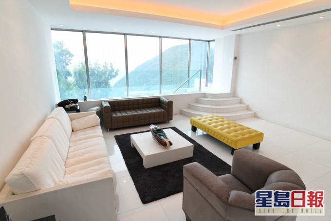 客廳擺放多組大型沙發，亦置黃色長椅，為簡約廳堂增添點綴。