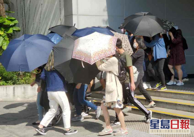 被告鄧智樂在傘陣掩護下離開法院。蕭文軒攝