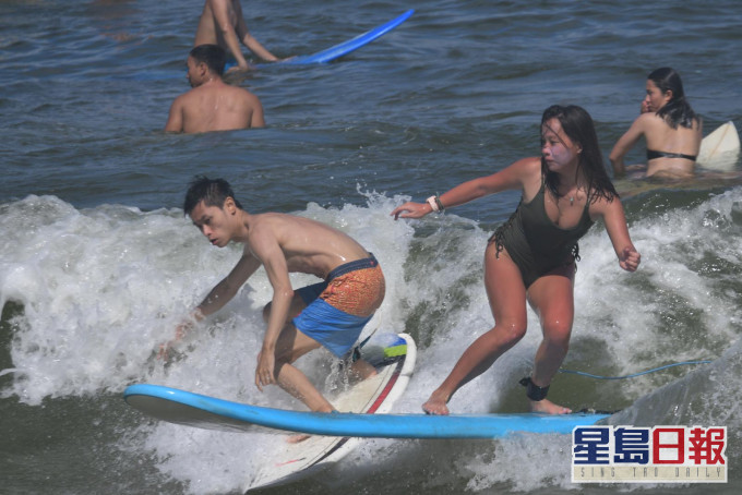 年輕人趁颱風逼近,風勢強勁,在大浪灣大玩衝浪。