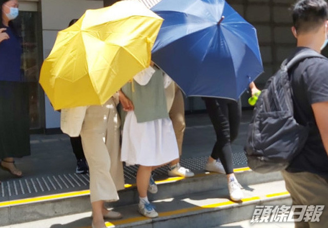 被告劉曉敏在傘陣下離開(綠白色衫)。 資料圖片