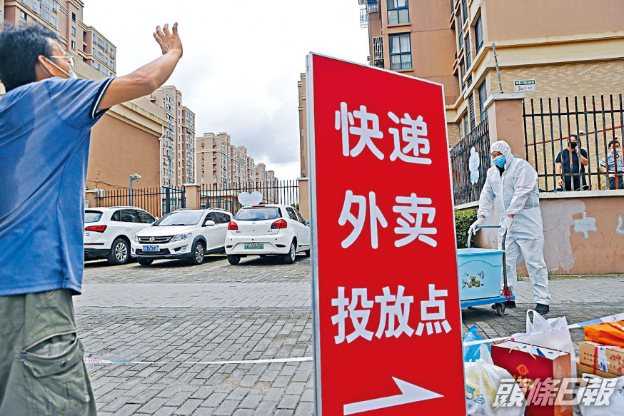 上海浦東心圓西苑小區被封,外賣員在門口交收。社區團購疫境大旺,學者料今年規模超過一千億元。