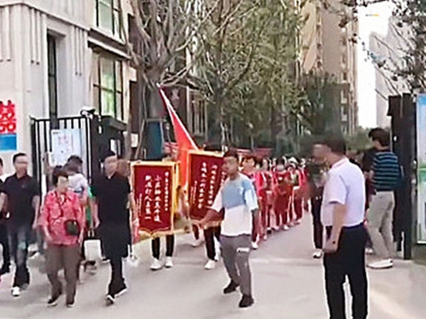 河南居民敲鑼打鼓將為鑫苑物業送上「欺壓打人佔第一」錦旗。(網圖)