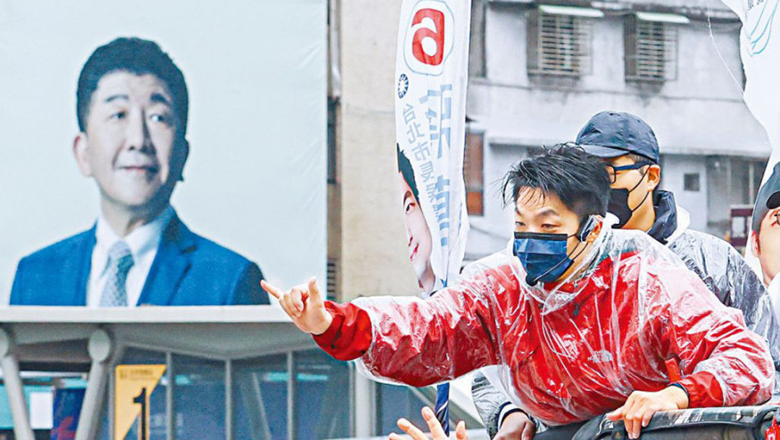 國民黨台北市長候選人蔣萬安(紅衣)昨天冒雨拜票。左方為民進黨對手陳時中的巨型宣傳板。